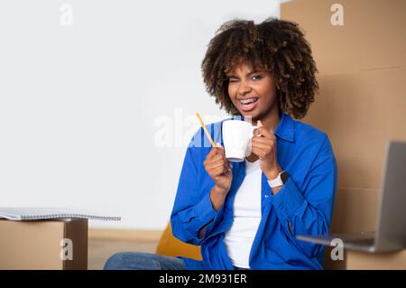 Glückliche Schwarze, Die Kaffee In Kartons Trinkt, Nachdem Sie Umgezogen Ist Stockfoto