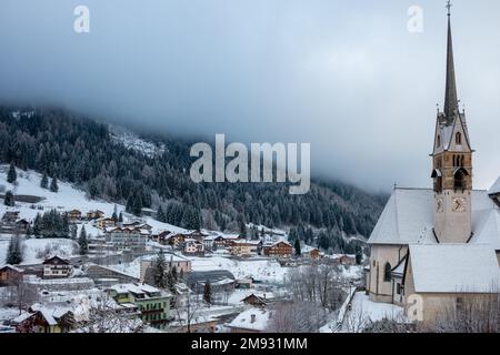 Moena, Dolomiten, Italien, Januar 16. 2023. Parrocchia di San Vigilio (Pfarrkirche San Vigilio) und andere Gebäude in Moena mit frischen s bedeckt Stockfoto