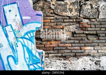 Wand in Ruinen mit Farbblöcken, die eine alte rote Backsteinwand verbergen. Stockfoto