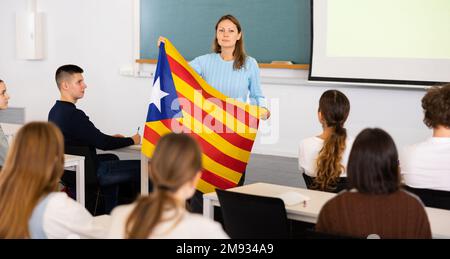 Geografie-Unterricht in der Schule - der Lehrer spricht über Katalonien und hält die Flagge in seinen Händen Stockfoto