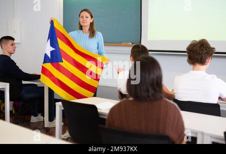 Geografie-Unterricht in der Schule - der Lehrer spricht über Katalonien und hält die Flagge in seinen Händen Stockfoto