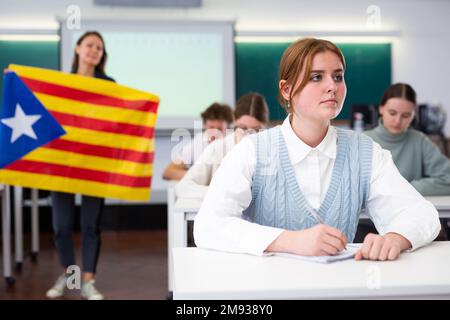 Geografie-Unterricht in der Schule - der Lehrer spricht über Katalonien und hält die Flagge in seinen Händen Stockfoto