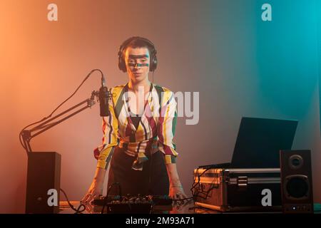 Musiker mit verrückter Make-up-Party, um Platten und Techno-Songs bei Tunrtables im Studio zu mischen. Verwendung des Mischers für Audiogeräte und Stereoinstrumente, Elektronik. Stockfoto