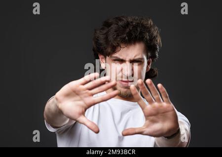 Junger, aufgebärdeter Mann, der Stopp-Gesten zeigt Stockfoto