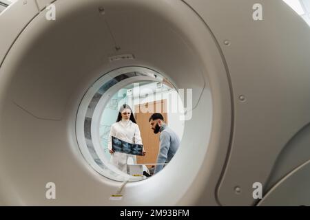 Der MRT-Arzt zeigt ein Röntgenbild des Abdomens eines Patienten. Sprechstunde nach MRT-Untersuchung in der Medizinischen Klinik Stockfoto