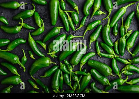 Draufsicht auf arrangierte Green Jalapeno Peppers auf dunklem Betonhintergrund Stockfoto