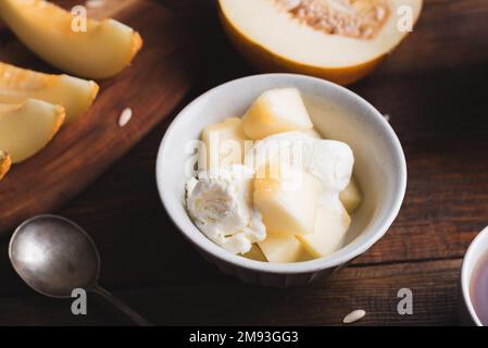 Vanille-Eis mit Honigtau-Melonenscheiben in der Schüssel Stockfoto