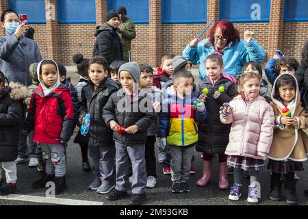 Lokale Schulkinder sehen sich die 2023 stattfindende Parade der Three Kings Day entlang der 3. Avenue in Spanish Harlem an, die von El Museo del Barrio, New Yorks führender lateinamerikanischer Kulturinstitution, ausgerichtet wird. Eine der großen künstlerischen Puppen des El Museo del Barrio, die jedes Jahr die Parade leiten. Stockfoto