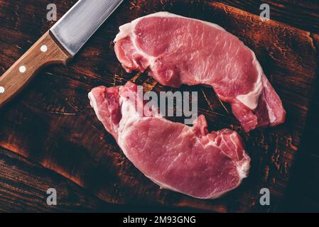 Zwei Schweinelende Steaks mit Messer auf rustikalen Schneidebrett Stockfoto