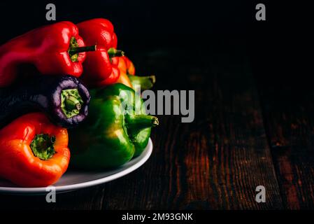 Bunte, frische Paprika auf dem Teller auf Holzboden Stockfoto