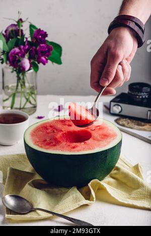 Der Löffel mit Stück Wassermelone in man Hand Stockfoto