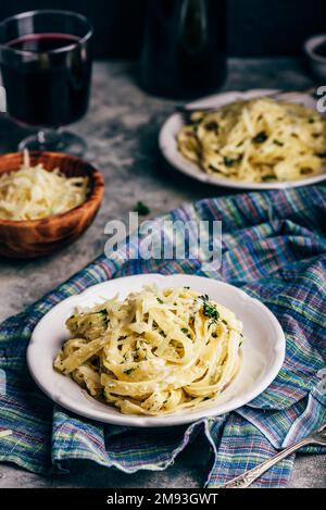 Zwei Portionen hausgemachte Pasta Alfredo auf weißem Teller mit geriebener Käseschale Stockfoto