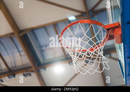 Ein kleiner Wurf eines Basketballkorbs in einer Turnhalle. Unscharfer Hintergrund. Sportkonzept. Hochwertiges Foto Stockfoto