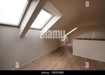 Leerer Raum mit Kastanienboden und cremefarbenen Wänden mit Oberlichtern in der abfallenden Decke Stockfoto