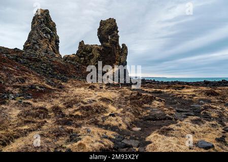 Fußweg zu den beeindruckenden Lóndrangar Basalt Felsspitzen an der Küste nahe Malarrif, Snæfellsjökull Nationalpark, Snæfellsnes, Island Stockfoto