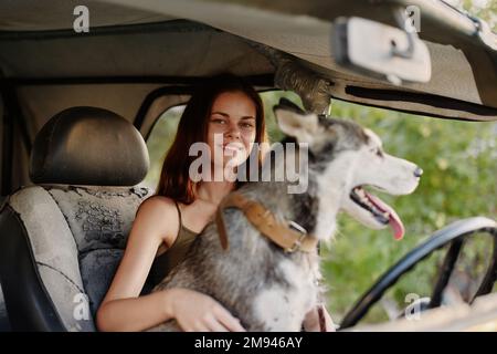 Frau und ihr Husky-Hund sind glücklich im Auto unterwegs Lächeln mit Zähnen Herbstspaziergang mit Haustier, Reisen mit Hundefreund Stockfoto