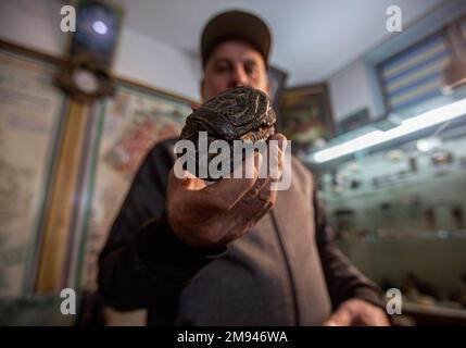 Palästinensischer Ramadan sammelt „Reichtum“ an Steinen und archäologischen Felsen in Gaza. Palästinensischer Ramadan Ahmed liebt es, in seinem kleinen Museum in seinem Haus in Khan Yunis, südlich des Gazastreifens, in die Tiefen der antiken Zivilisationen einzutauchen, wo er liebend gerne eine Gruppe kostbarer Artefakte erwirbt, darunter den jemenitischen Achatstein, den Sijil-Stein, der im Heiligen Koran erwähnt wird, Kristalle und transparente Steine, der berühmte Fingerabdruckstein und der Mondmeteoritenstein, einer der seltensten Arten der Welt, Steine, die mit seltsamen Formen aus der Antike bemalt sind. Stockfoto