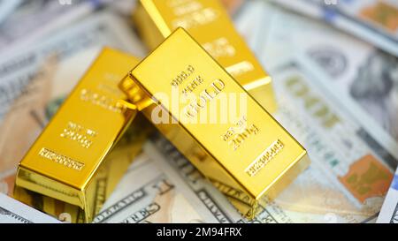 Nahaufnahme von Goldbarren auf vielen US-Dollar-Scheinen. Stockfoto