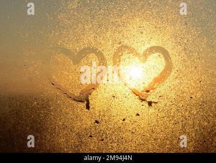 2 Liebesherzen, gezeichnet mit einem Finger auf dem beschlagenen Fensterglas. Valentinstag, Valentinstag, kreativ Stockfoto