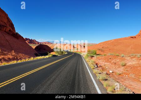 Eine Straße, die durch Sandsteinformationen im Valley of Fire State Park, Nevada, USA führt. Den amerikanischen Südwesten erkunden. Stockfoto