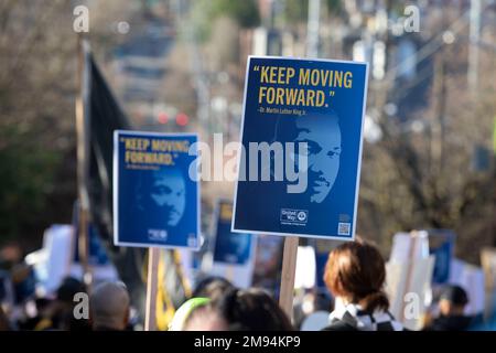 Seattle, Washington, USA. 16. Januar 2023. Die Teilnehmer halten Schilder mit der Aufschrift „Keep Moving Forward“ auf einem marsch durch Seattles Central District, um das Leben und Werk von Martin Luther King Jr. zu feiern Dieses Jahr ist der Seattle MLK Jr. Organisation der 40.-jährigen Ehrung des Erbes von Dr. Kings durch die Koalition. Kredit: Paul Christian Gordon/Alamy Live News Stockfoto