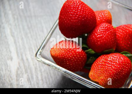 Früchte rote Erdbeeren in Glasschüssel auf altem grauen Holzhintergrund Stockfoto