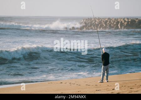 Teenager Angeln mit Angelrute am Strand bei Sonnenuntergang Stockfoto