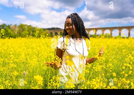 Ein schwarzes Mädchen mit Zöpfen auf einem Feld gelber Blumen Stockfoto