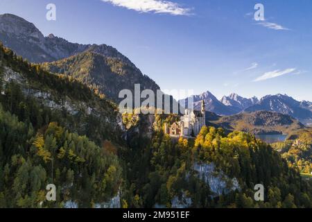 Aus der Vogelperspektive sehen Sie Schloss Neuschwanstein in Schwangau, auf der rechten Seite den Alpsee und Schloss Hohenschwangau, im Hintergrund das Tannheim-Gebirge Stockfoto