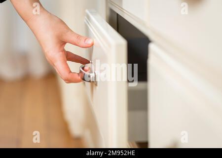 Nahaufnahme der Hand einer Frau öffnet die Schublade des Küchentisches Stockfoto