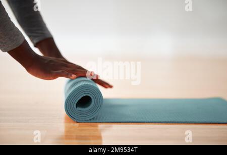 Diese Matte hat mich weit gebracht. Eine Person, die nach dem Unterricht ihre Yoga-Matte hochrollt. Stockfoto