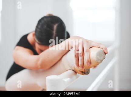 Ballerinas streben immer nach Perfektion. Eine junge Balletttänzerin, die sich gegen eine Barre lehnt. Stockfoto