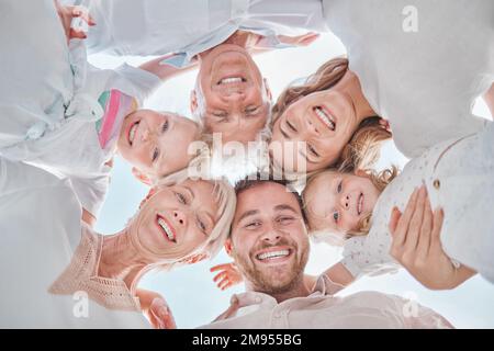 Fröhliche weiße Familie, die sich mit Blick nach unten versammelt und die Zeit in der Natur genießt. Ein kleiner Winkel der Gesichter einer sorglosen Familie, die sich umarmt Stockfoto