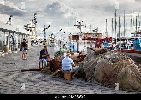 Ein alter Fischer, der Fischernetze im Hafen von Palermo abfackelt Stockfoto