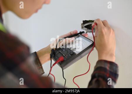 Elektriker, der Elektrokabel installiert und den Strom in einer elektrischen Anlage prüft Stockfoto