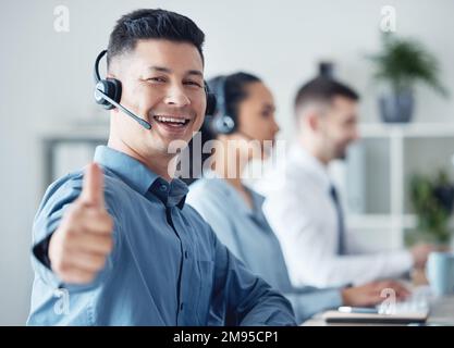 Ich bin so nah dran, mein Ziel zu erreichen. Porträt eines jungen Callcenter-Agenten, der Daumen nach oben zeigt, während er mit seinen Kollegen im Büro arbeitet Stockfoto