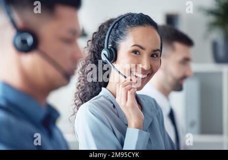 Sie hat eine klare und freundliche Telefonstimme. Porträt einer jungen Callcenter-Agentin, die neben ihren Kollegen in einem Büro arbeitet. Stockfoto