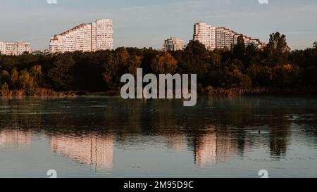 Die Tore der Stadt in der Nähe eines Herbstwaldes spiegeln sich in einem See mit vielen Enten wider Stockfoto