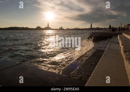 Blick auf Venedig bei Sonnenuntergang von der Riva degli Schiavoni, mit dem San Mark Turm in der Ferne Stockfoto