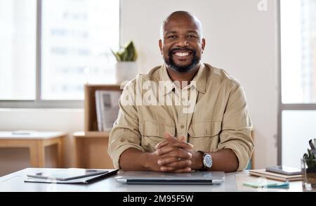 Willkommen in meinem Büro. Porträt eines erwachsenen Geschäftsmannes, der an seinem Schreibtisch in einem modernen Büro arbeitet. Stockfoto