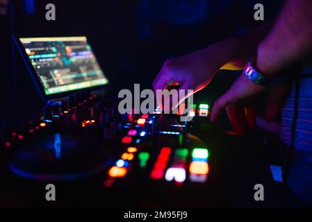 Hände eines professionellen DJs, der Musik für eine Pyjamaparty spielt und mixt, und die Drehmomentregler der Konsole Stockfoto