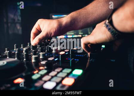 DJ mischt die Piste im Nachtclub in Partyhänden, die Controller fahren Stockfoto