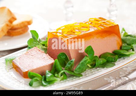 Köstliche Ostervorspeise zum Weihnachtsessen. Hähnchenleberpastete mit Gelee und frischem Maissalat auf weißem Gericht. Stockfoto