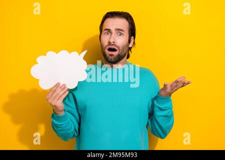 Foto eines beeindruckt geschossenen Mannes Tragen Sie türkisfarbene Kleidung, die die Sprechblase hält leerer Raum isolierter gelber Hintergrund Stockfoto