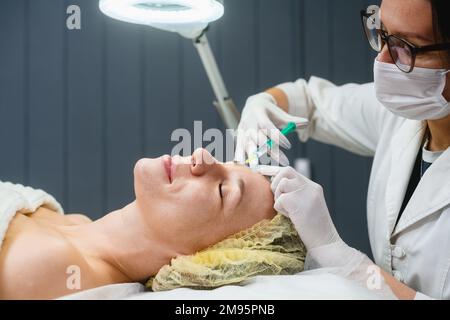 Professionelle Kosmetikerin Hautinjektionen bei weiblichen Stirn-, Anti-Aging- und Falten-Gesichtspflege in Innenräumen anwenden Stockfoto