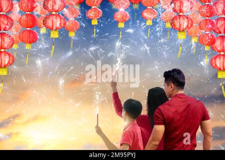 Chinesische Neujahrslaternen und Feuerwerk. Die Familie feiert das neue Jahr des Lunars. Asiatische Eltern und Kind mit Knallern. Feier in Asien. Stockfoto