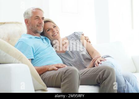 Seniorenpaar, Ruhestand und Nachdenken auf dem Sofa zu Hause mit Liebe, Pflege und Unterstützung durch die Lebensversicherung. Engagement von Mann und Frau bei Gesunden Stockfoto