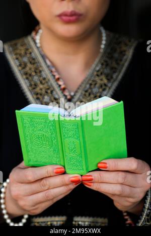 Muslimische Frau liest einen grünen Heiligen Koran auf arabisch. Nahaufnahme. Stockfoto