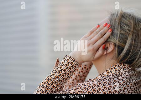 Eine Frau, die ihr Gesicht mit der Hand bedeckte. Depression. Stockfoto
