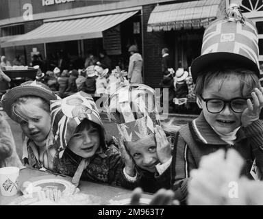 ELISABETH Ill'S SILBERJUBILÄUM Eine Teeparty für Kinder in einer Straße in Horley. Ein Mädchen hat ein Bild von der Königin auf dem Hut. Ein anderer trägt eine Krone. Stockfoto